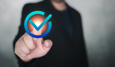 Man in suit hand touch a sign of checkmark to standard quality control certification assurance guarantee. Certification standards, quality control, service assurance for business process automationの写真素材