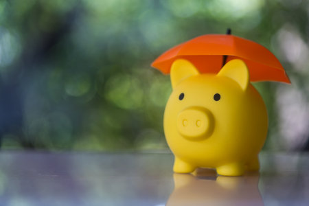 Yellow piggy bank with orange umbrella concept for finance insurance, protection, safe investment or banking. Financial insurance and protectionの写真素材