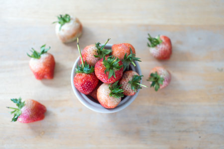 Fresh ripe delicious strawberries in bowl on wood tableの写真素材