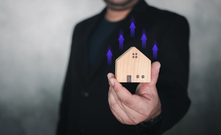 Increased value of real estate or property house concept. Real estate investment marketing analysis. Businessman holding home with icon grown up of income of property value, land price, property tax.の写真素材