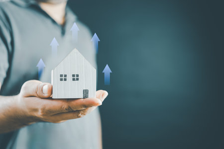 Increased value of real estate or property house concept. Real estate investment marketing analysis. Man holding home with icon grown up of income property value, earning profit investor strategy.の写真素材
