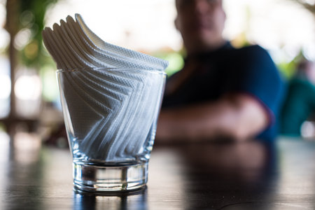 Selective focus on white paper tissue in glass on wood table at coffee shopの写真素材