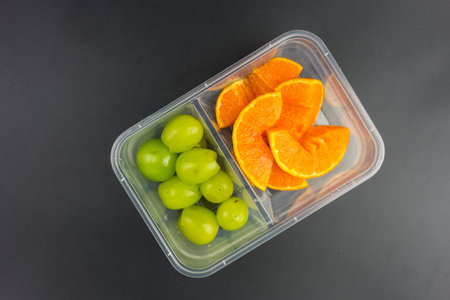 Ripe orange and green grapes in a takeaway plastic box. Top viewの写真素材