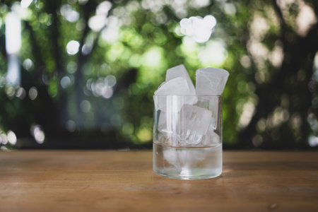 Glass of ice and water on wood table, homemade ice cubesの写真素材