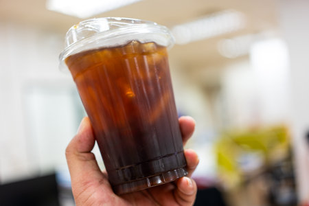 Iced black coffee or americano blend in plastic cup in hand. Close upの写真素材