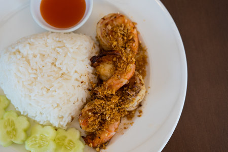 Fried shrimp with garlic and pepper and cooked Thai jasmine rice in white plate, popular Thai foodの写真素材