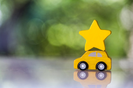 Wood yellow toy car carry a yllow star on roof against nature background, the scoring satisfaction surveysの写真素材