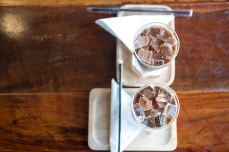 Two iced mocha coffee. Espresso coffee mixed chocolate put in ice in long glass on wooden table in cafe.の写真素材