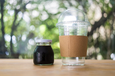 Cold coffee bottle and empty glass on the wooden table. Relaxing with iced coffee at home.の写真素材