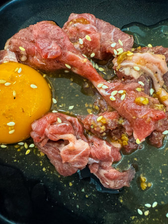 Marinated pork, egg, and sesame on black dish for hot potの写真素材