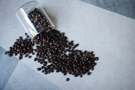 Pile of roasted coffee beans from glass cupの写真素材