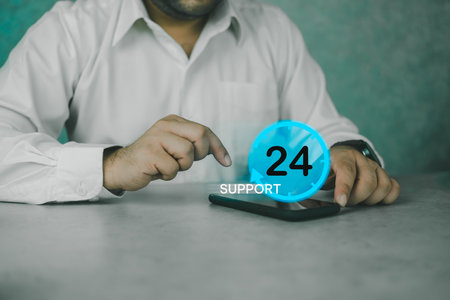 Nonstop service concept. Nonstop business internet technical support work. Man use smart phone with virtual 24-7 clock, worldwide web full-time available contact of service. Always customer serviceの写真素材