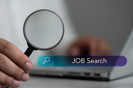 A man hold a magnifier to find job with search icon bar, seeking into right job. Behind that has used laptop put in front of him. Data search technology search engine optimization. HRM conceptの写真素材