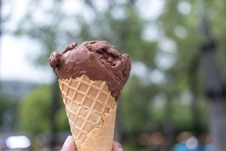 A male hand holding an ice cream chocolate in waffle cone. Vacation and fun, relax and enjoyの写真素材