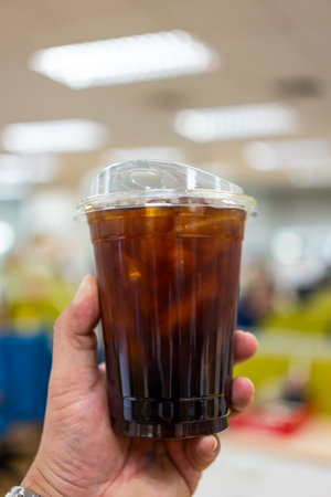 Holding disposable iced black coffee in plastic cup before drinking.の写真素材