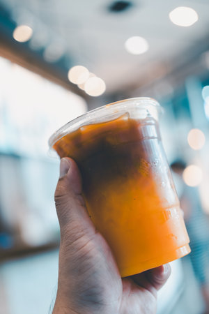 Hand holding ice coffee with orange juice at coffee shop.の写真素材