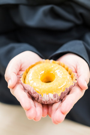 Woman hand delicately holds a delicious sweet glazed donut. Close upの写真素材