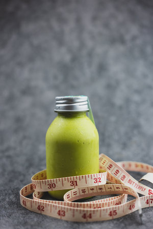 A bottle of smoothies mix with honey and milk with white measuring tape. Weight loss conceptの写真素材