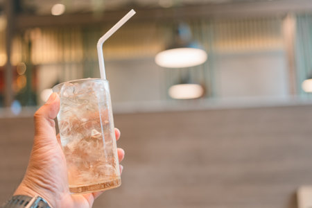 Close up of iced tea with ice cubes and white straw in handの写真素材