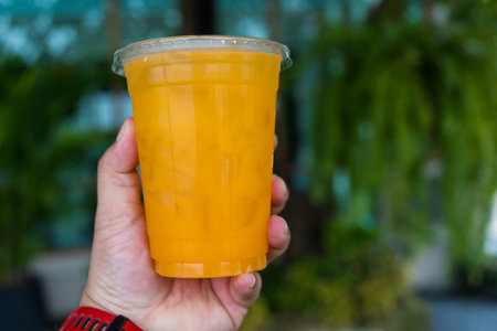 Orange juice ice in plastic cup. Healthy orange juice detox green nature backgroundの写真素材