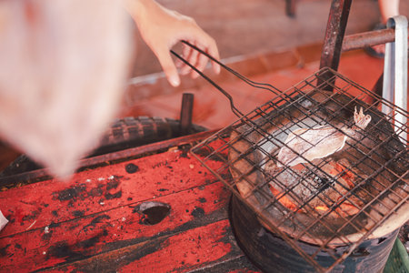 Close up of the vendor is grilling squid grill with dried squids, delicious seafood snacks in Thailand. Artificial dried grill on fire.の写真素材