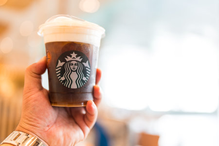 Bangkok, Thailand - June 23, 2024 : Man holding a Starbucks cold brew beverage cup in hand. Starbucks cold brew beverageのeditorial素材