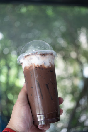 Hand holdign ice Mocha coffee with fresh milk against nature backgroundの写真素材