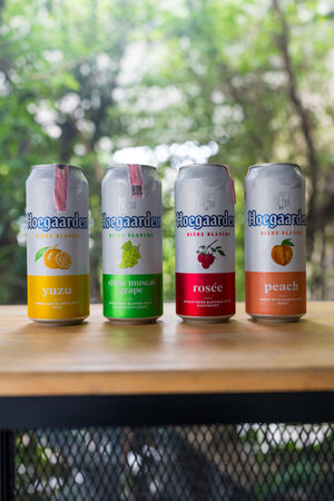 Samut Prakan, Thailand - July 5, 2024 : A popular Hoegaarden beer four flavors include Yuzu, Shine muscat grape, Rosee, and peach put on wood table. A popular imported beer in Thailandのeditorial素材
