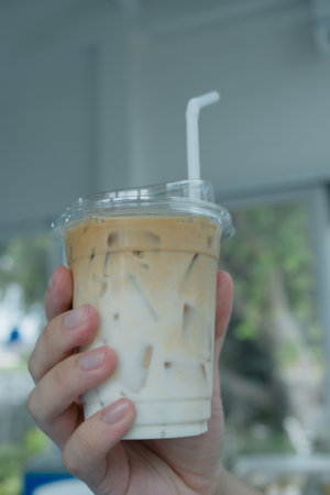 Cool iced latte coffee, the bottom as milk top by coffee shot in a plastic glass on handの写真素材