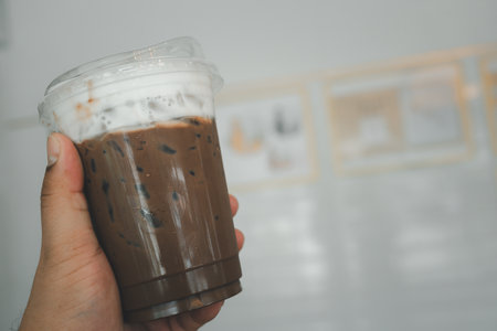 Iced coffee mocha with milk foam in man hand at coffee shop.の写真素材