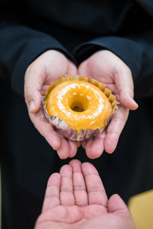 Hand give delicious glazed donut with delicately to friend. Close upの写真素材