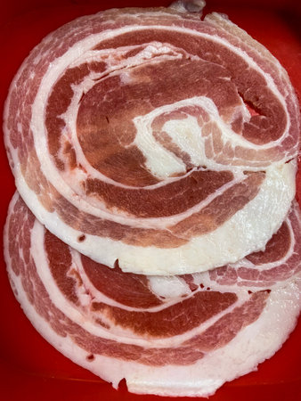 Thin pork belly slices on red tray for hotpotの写真素材