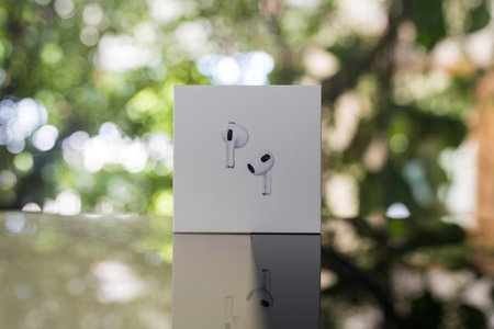Bangkok, Thailand - September 2, 2024 : Man hand holding a AirPods 3 generations. Headphones from the apple company in packagingのeditorial素材
