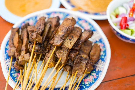 Liver satay or liver pork in bamboo skewers eaten with peanut sauce or sweet and sour sauce. Asian food concept style and Thai foodの写真素材