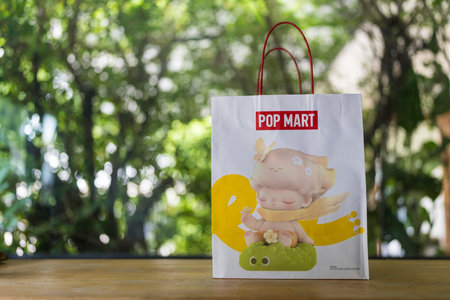 Bangkok, Thailand - September 16, 2024 : White paper shopping bag with red handle from POP MART on table. POP MART is the largest and fastest growing pop-toy maker in China.のeditorial素材