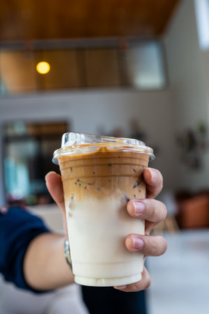 Cup of ice cafe latte with two layer, espresso and fresh milk in handの写真素材