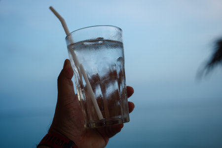 Hand holding a glass of water with iceの写真素材
