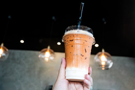 Ice Thai milk tea  with milk on hand, popular drink menu in Thailandの写真素材