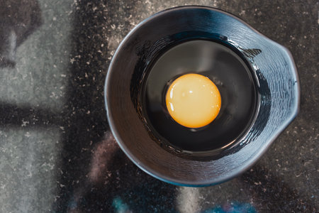 Fresh broken organic chicken egg in black bowlの写真素材