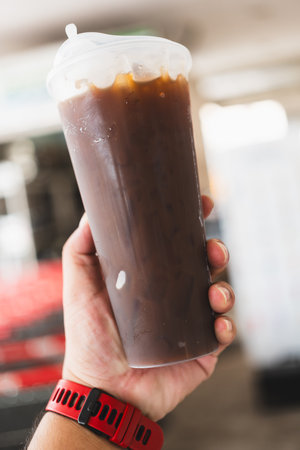 Man hand showing a take away plastic cup of iced black coffeeの写真素材