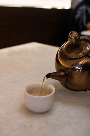 Hand pouring hot tea from copper teapotの写真素材