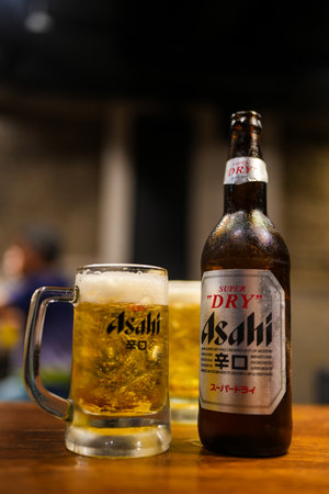 Bangkok, Thailand - October 26, 2024 : Asahi beer bottle and Asahi beer with foam in a glass on...