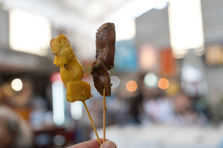 Hand keep holding liver pork and pork satay in bamboo skewers. Asian food concept style and Thai foodの写真素材