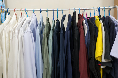 Collection of clothes hanging on rack at homeの写真素材