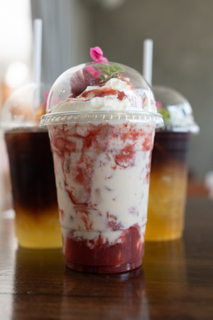 Strawberry yogurt smoothie in take away glass on wood table at cafeの写真素材