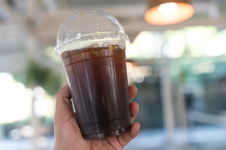 Tasty iced americano coffee on hand at coffee shopの写真素材