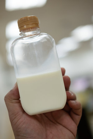 A fresh of milk in plastic bottle with golden lid on man handの写真素材