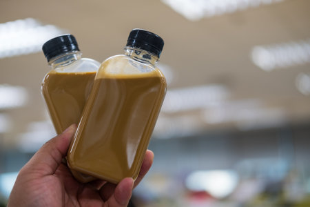 Man hand holding two bottles of iced coffee latte. The concept of takeaway and delivery.の写真素材