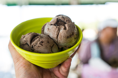 Scoop of chocolate ice cream in green bowl on handの写真素材