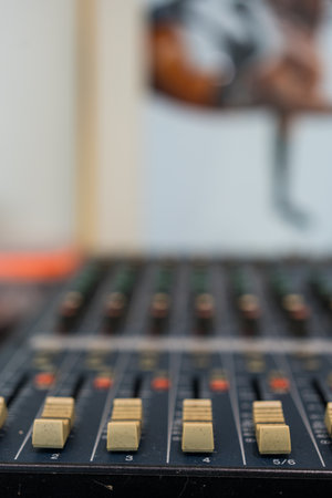 Amplifying equipment adjusts studio audio mixer knobs and faders. Selective focus